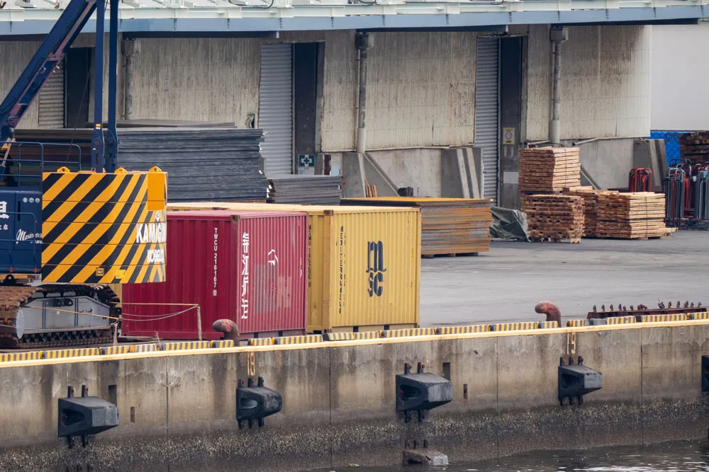 港に置かれた黄色いコンテナと周囲のコンテナが写るcontainerの問題画像