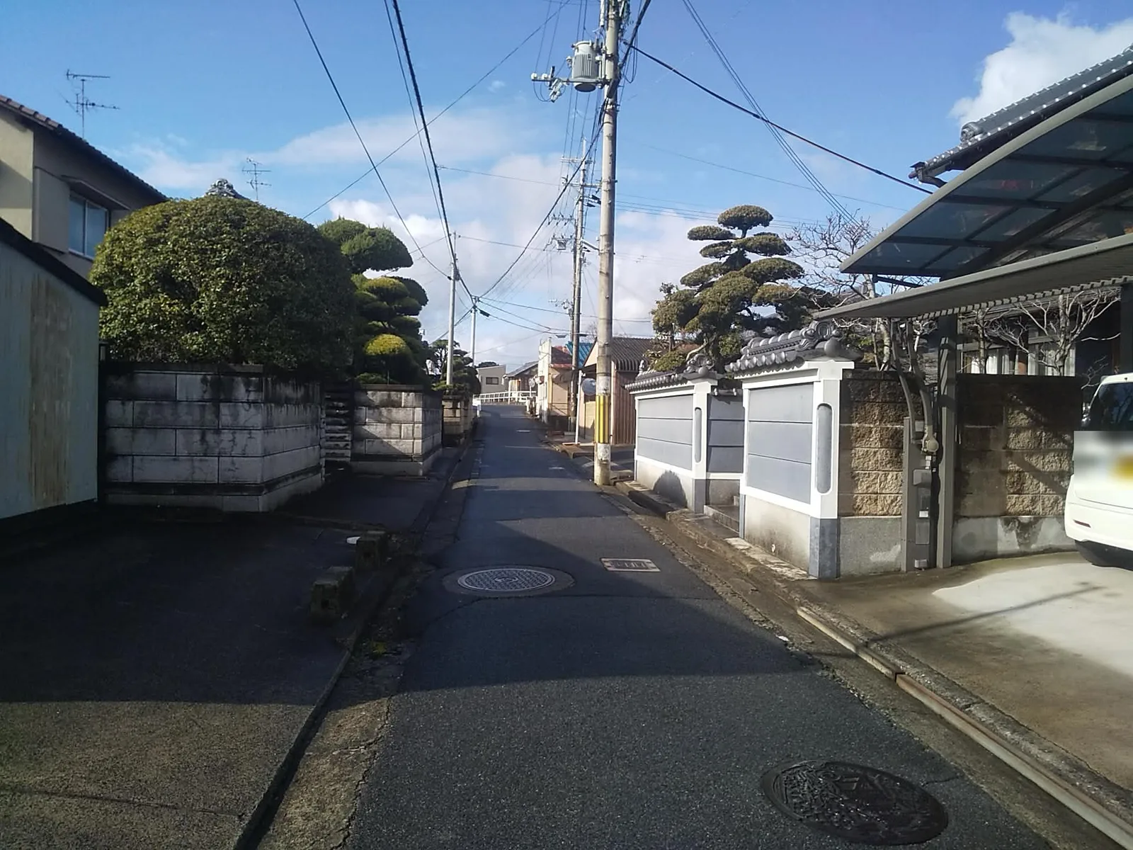 住宅街、電柱、マンホールが写るhousesの問題画像。車両ナンバーは匿名化済み